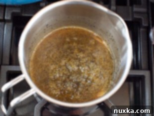 Poppy seed mustard sauce for ham and cheese sliders boiling in a saucepan.