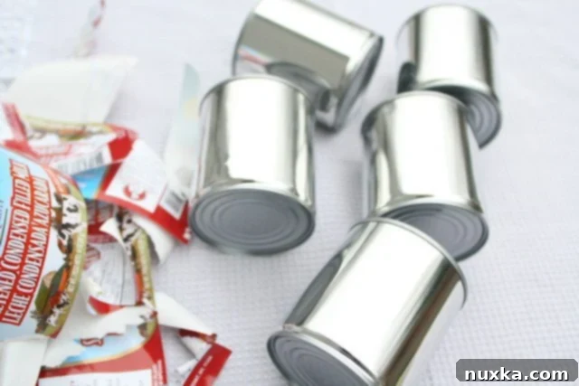 Cans of condensed milk with labels removed, placed inside a large pot.