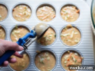 Healthy zucchini muffin batter in a baking pan with liners