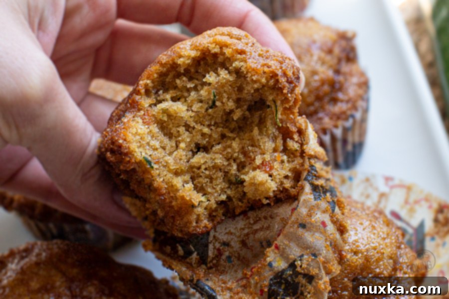 A bite taken out of a moist zucchini muffin, showcasing its texture