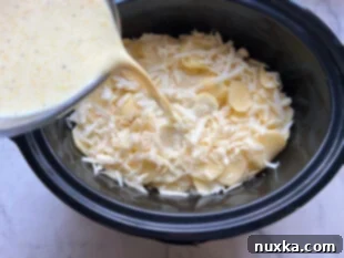 pouring the milk mixture over the layers of scalloped potatoes