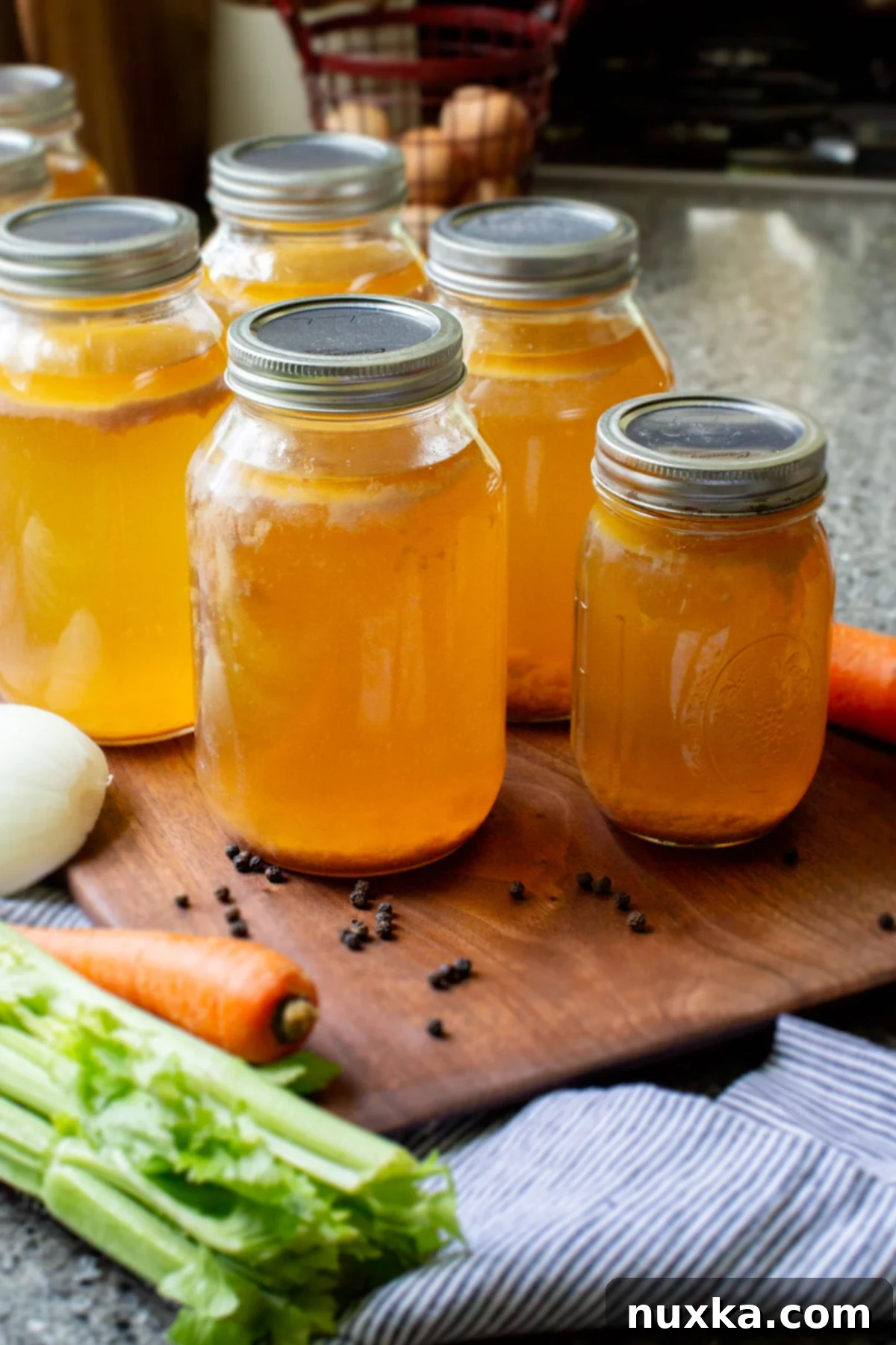 Homemade canned chicken broth jars on a rustic wooden surface, ready for storage.