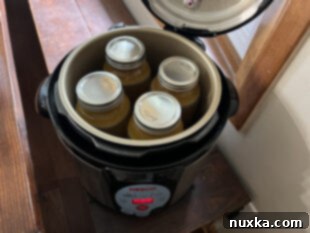 Jars of chicken broth placed into a pressure canner for processing.