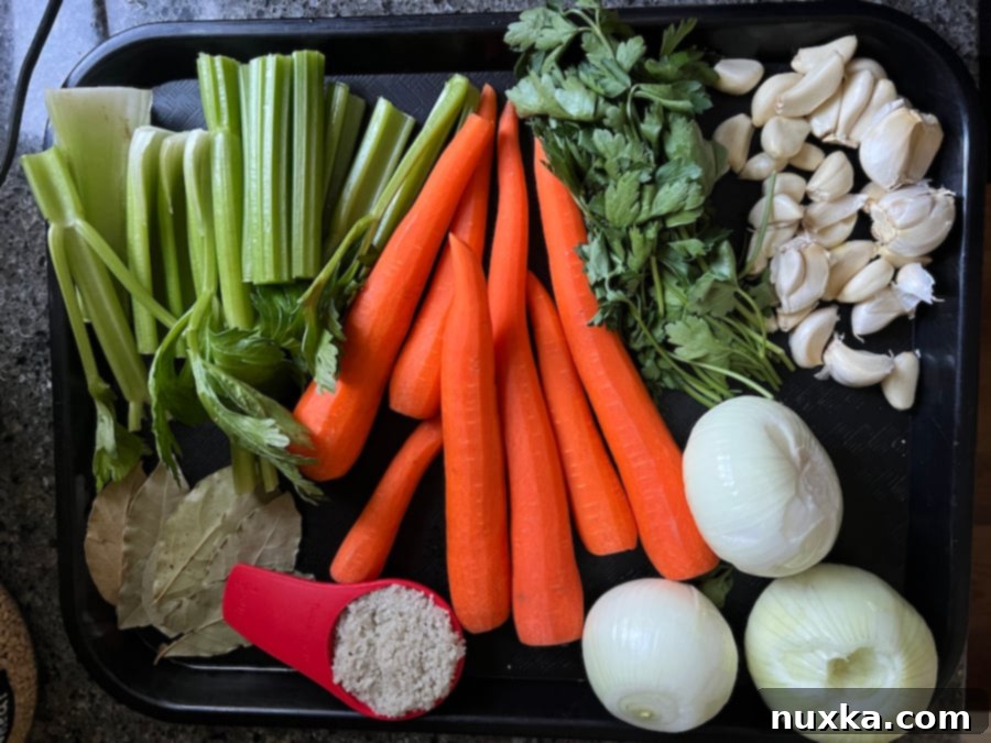 A selection of raw ingredients for chicken bone broth including chicken bones, carrots, celery, onions, garlic, and parsley.