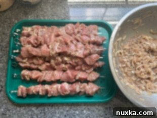 Threading marinated pork onto metal skewers for shashlik