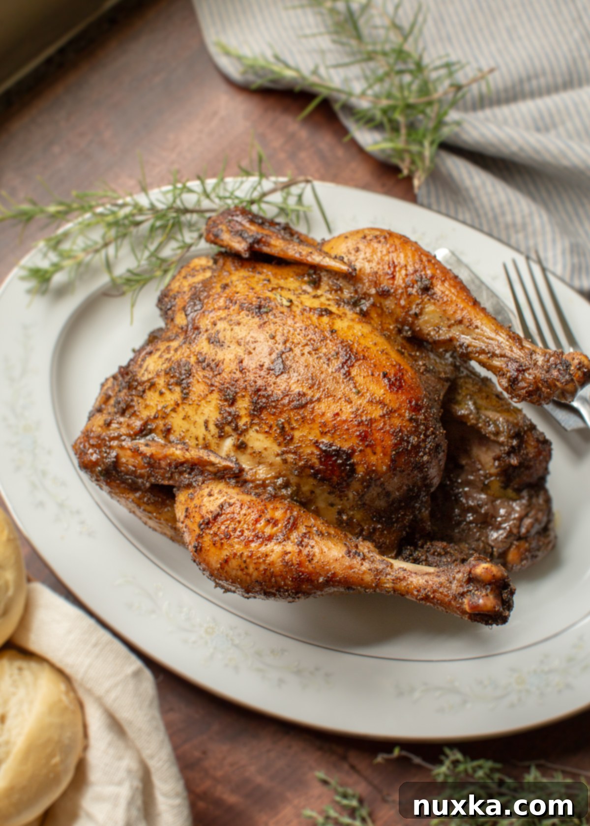 roasted chicken on an oval dish decorated with herbs 