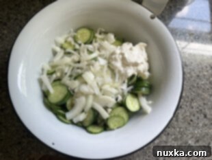 cucumbers and onion in a mixing bowl for creamy cucumber salad