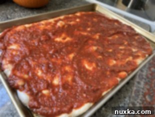 chunky tomato sauce over the soft sourdough focaccia pizza bread dough