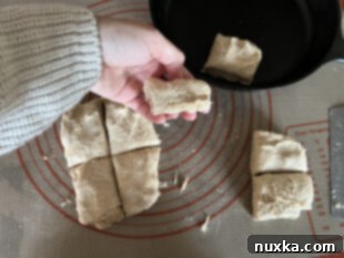 cutting square biscuits and arranging in cast-iron pan