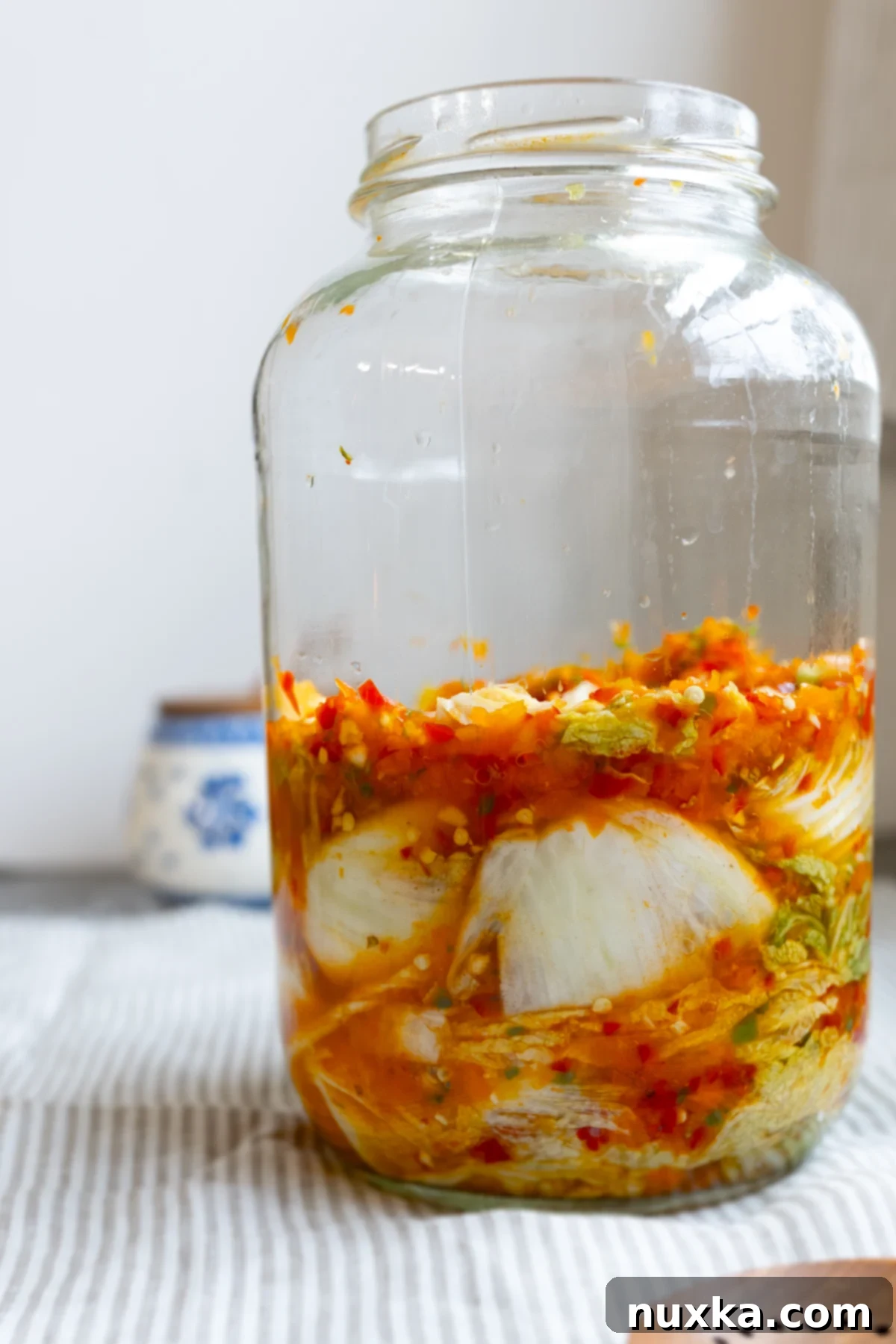 Simple homemade kimchi packed into a glass jar, showcasing its vibrant red color and texture