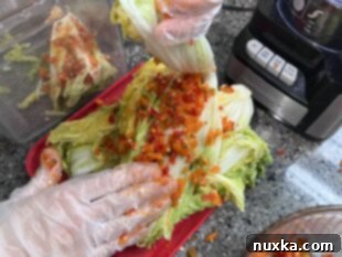 Rubbing the spicy pepper mixture onto each napa cabbage leaf for homemade kimchi