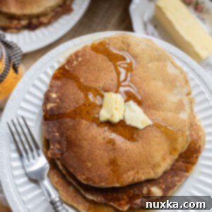 Fluffy Whole Wheat Sourdough Pancakes 5 whole wheat sourdough pancakes served on a plate with butter and maple syrup