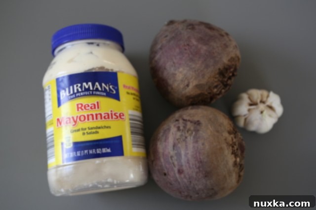 Ingredients laid out for baked beet salad: whole beets, mayonnaise, and garlic cloves