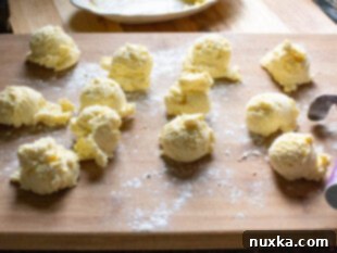 Russian cottage cheese pancakes called Syrniki being shaped on top of a floured cutting board