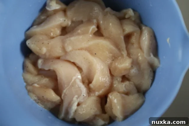 Seasoned chicken strips in a bowl, after being treated with baking soda and vinegar.