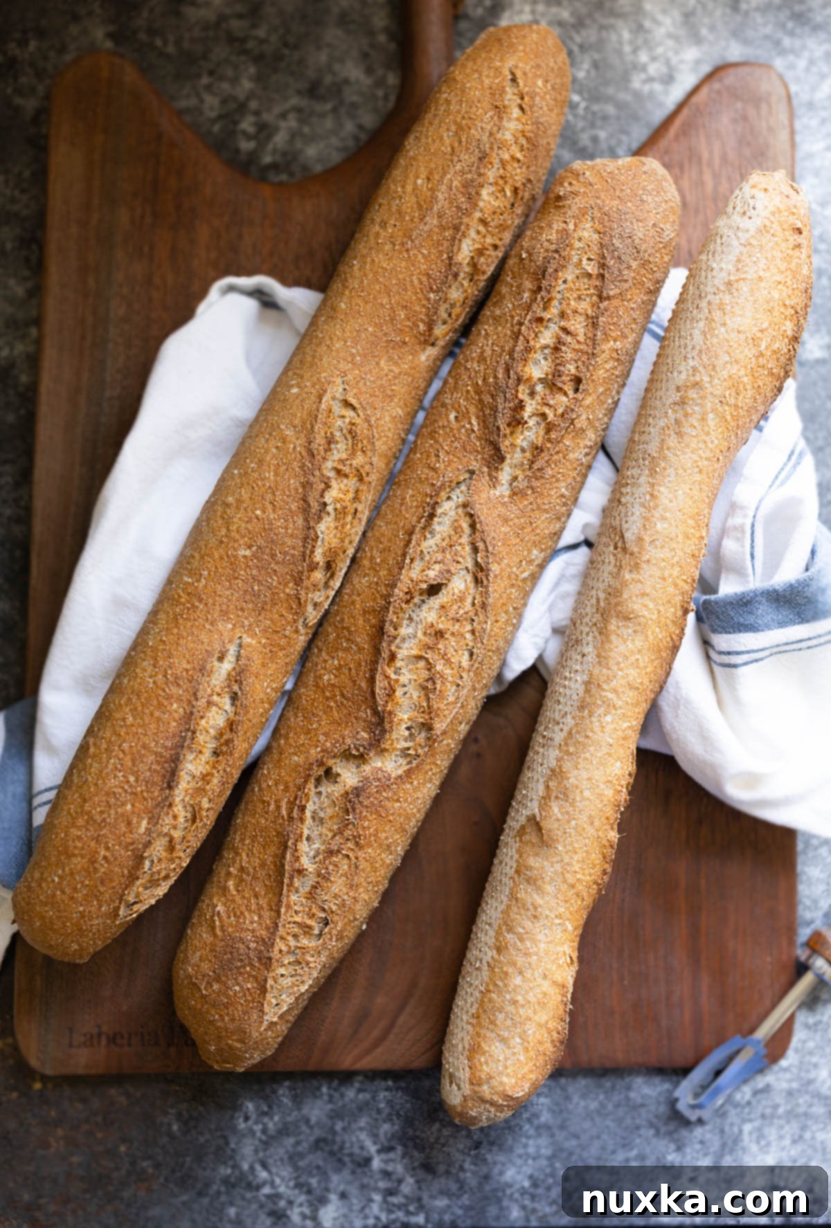whole wheat sourdough baguettes made from freshly milled flour on a cutting board with a kitchen towel
