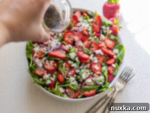 Assembling spinach strawberry salad in a large bowl