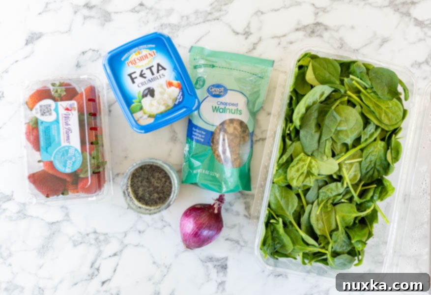 All ingredients for Spinach strawberry salad (baby spinach, walnuts, red onion, homemade poppy seed dressing, feta cheese, and fresh in season strawberries).