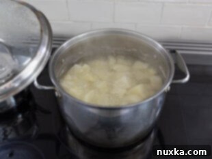 Potatoes boiling in a large pot on the stove for mashed potatoes.