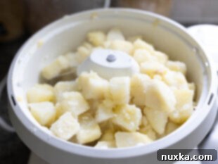 Drained, cooked potatoes in a colander, steaming, with a stick of butter melting over them.