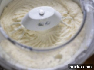 Fluffy mashed potatoes mixing in a Bosch stand mixer, becoming airy and creamy.