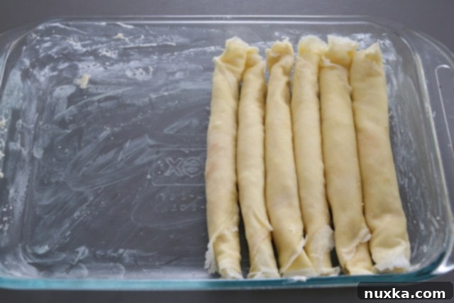 rolled crepes in baking dish ready for the next layer