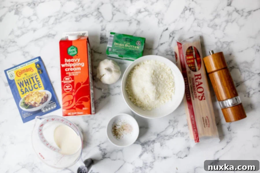 ingredients for homemade Olive Garden sauce (white base packet, heavy cream, milk, chopped garlic, salt, pepper, butter, fettuccine pasta, and parmesan cheese)