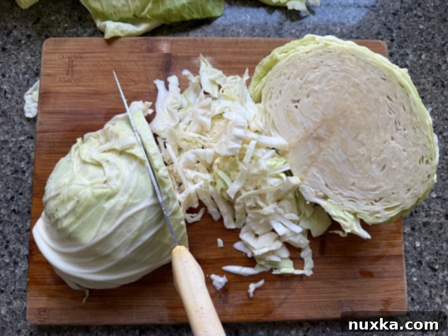 Chopping the cabbage for traditional sauerkraut by hand with a sharp knife on a wooden cutting board