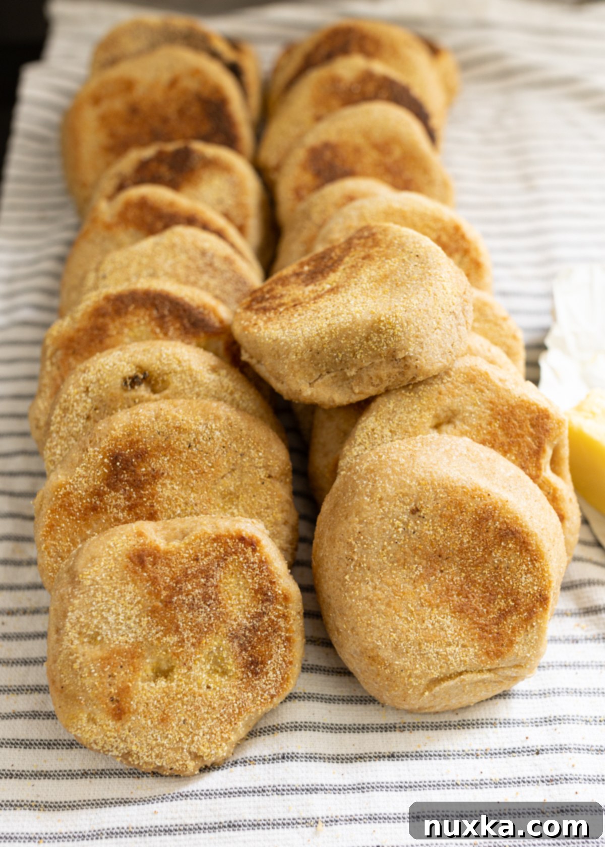 A stack of perfectly browned whole wheat English muffins, made from 100% whole grains, showing their inviting texture