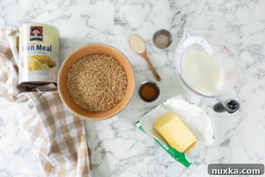 All the ingredients for Whole wheat English muffins laid out: kefir, butter, dry active yeast, honey, salt, hard white wheat berries, and cornmeal, ready for baking.