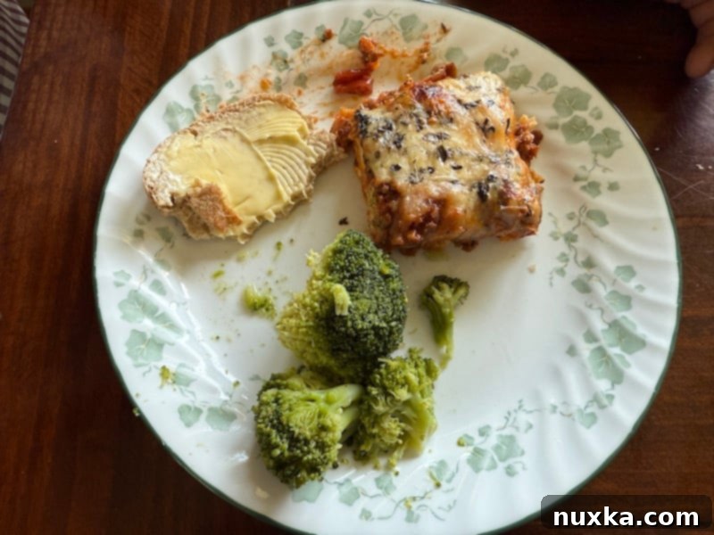 The Ultimate Freezer Lasagna 5 image of how to serve freezer lasagna (prepared freezer lasagna is baked and served with steamed broccoli and garlic bread on a dinner plate).
