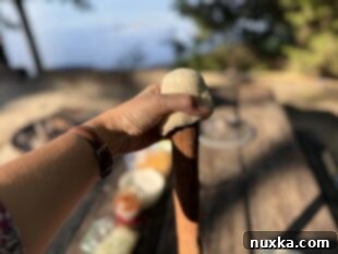 Hands pulling biscuit dough over a roasting stick to form a cup shape for Woof Em Sticks
