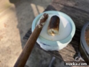 Close-up of a perfectly cooked Woof Em Stick, golden brown and fluffy, ready to be removed from the roasting stick