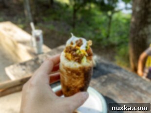 A finished Woof Em Stick filled with a generous serving of taco meat, crisp lettuce, cheese, and salsa