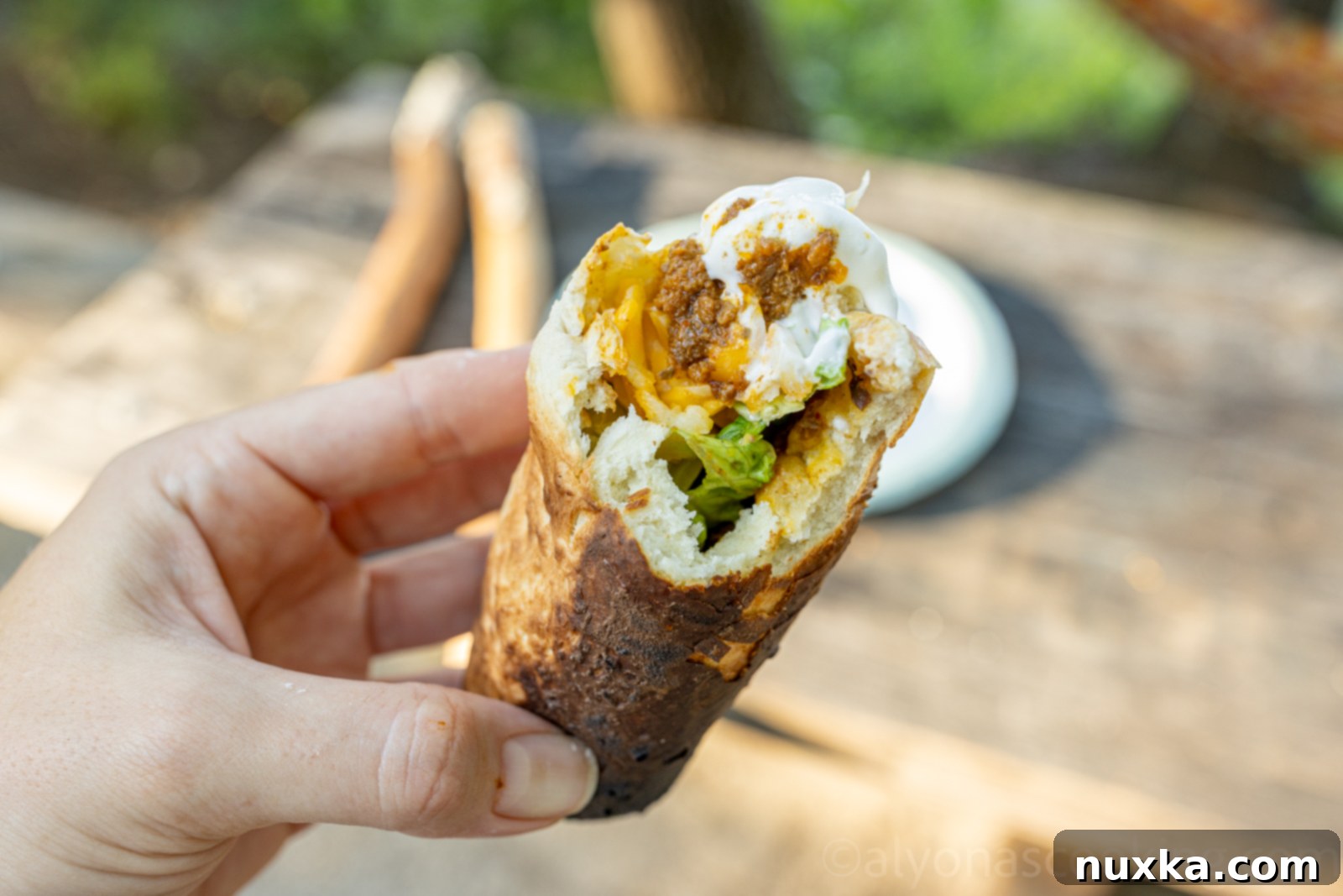 A freshly made Woof Em Stick overflowing with savory taco fillings like seasoned meat, shredded cheese, and vibrant salsa, with a soft, fluffy biscuit base
