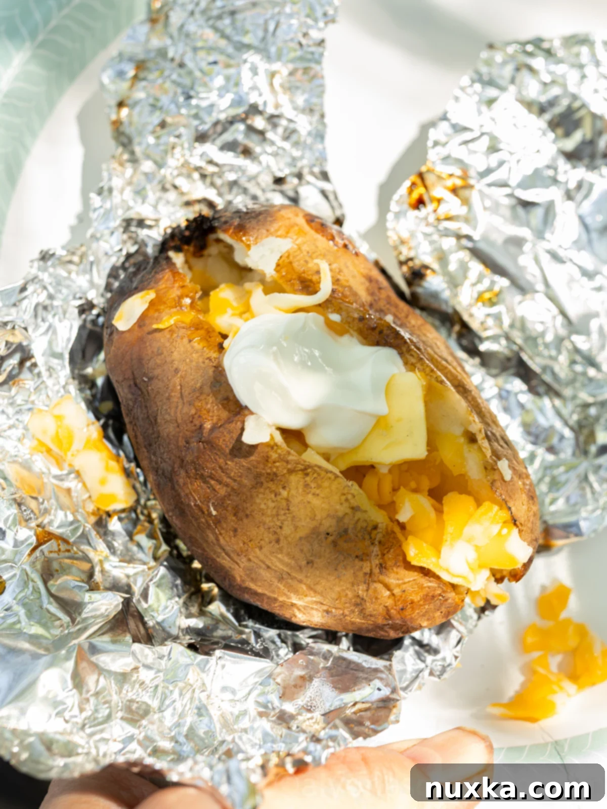 image of baked potatoes cooked from the fire (unwrapped from foil and topped with butter, cheese, and sour cream)