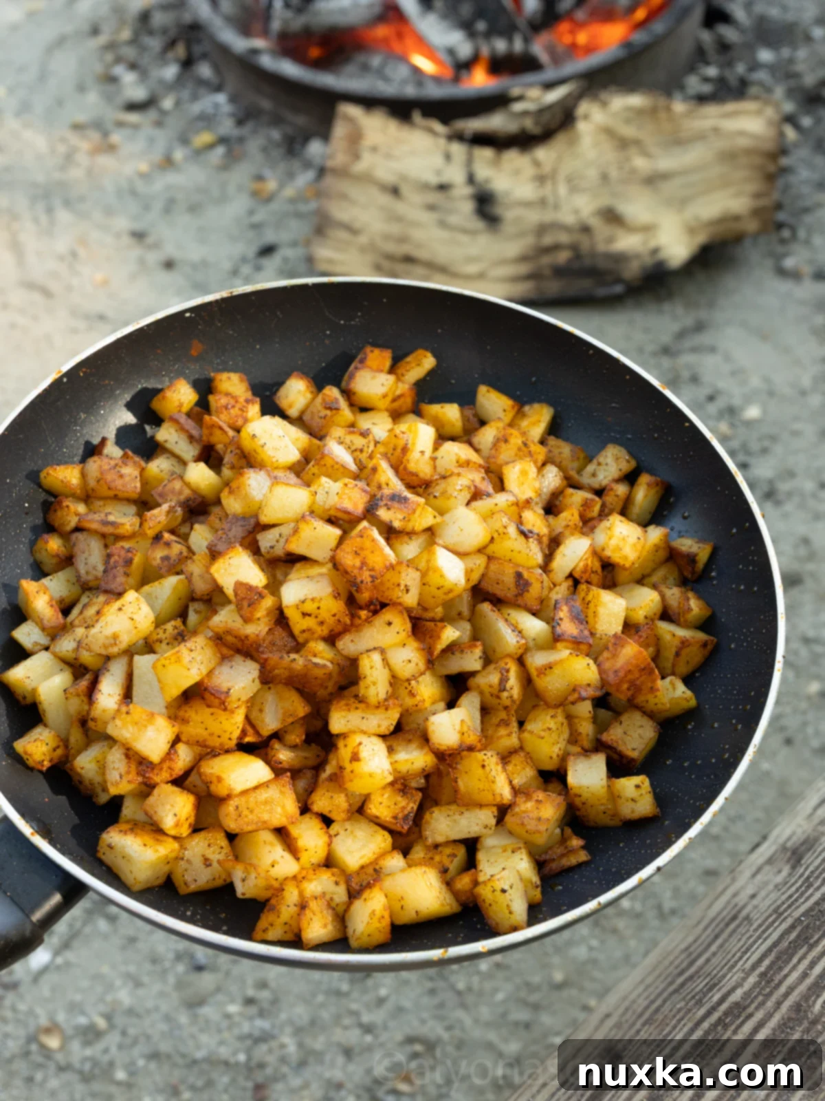 image of campfire breakfast potatoes on a skillet near a hot fire 