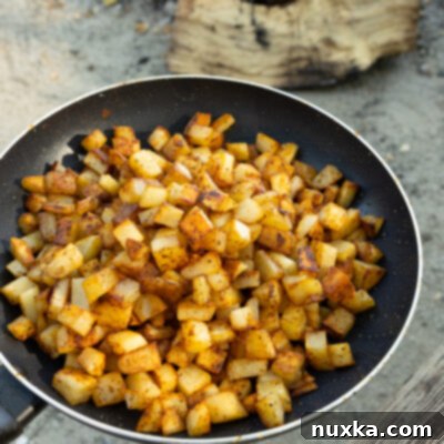 Golden Campfire Hash 13 image of campfire breakfast potatoes on a skillet near a hot fire
