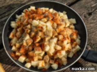 image of breakfast potatoes seasoned with paprika, garlic salt, and black pepper on a skillet outdoors
