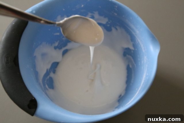 Homemade powdered sugar glaze in a white bowl, ready to be drizzled