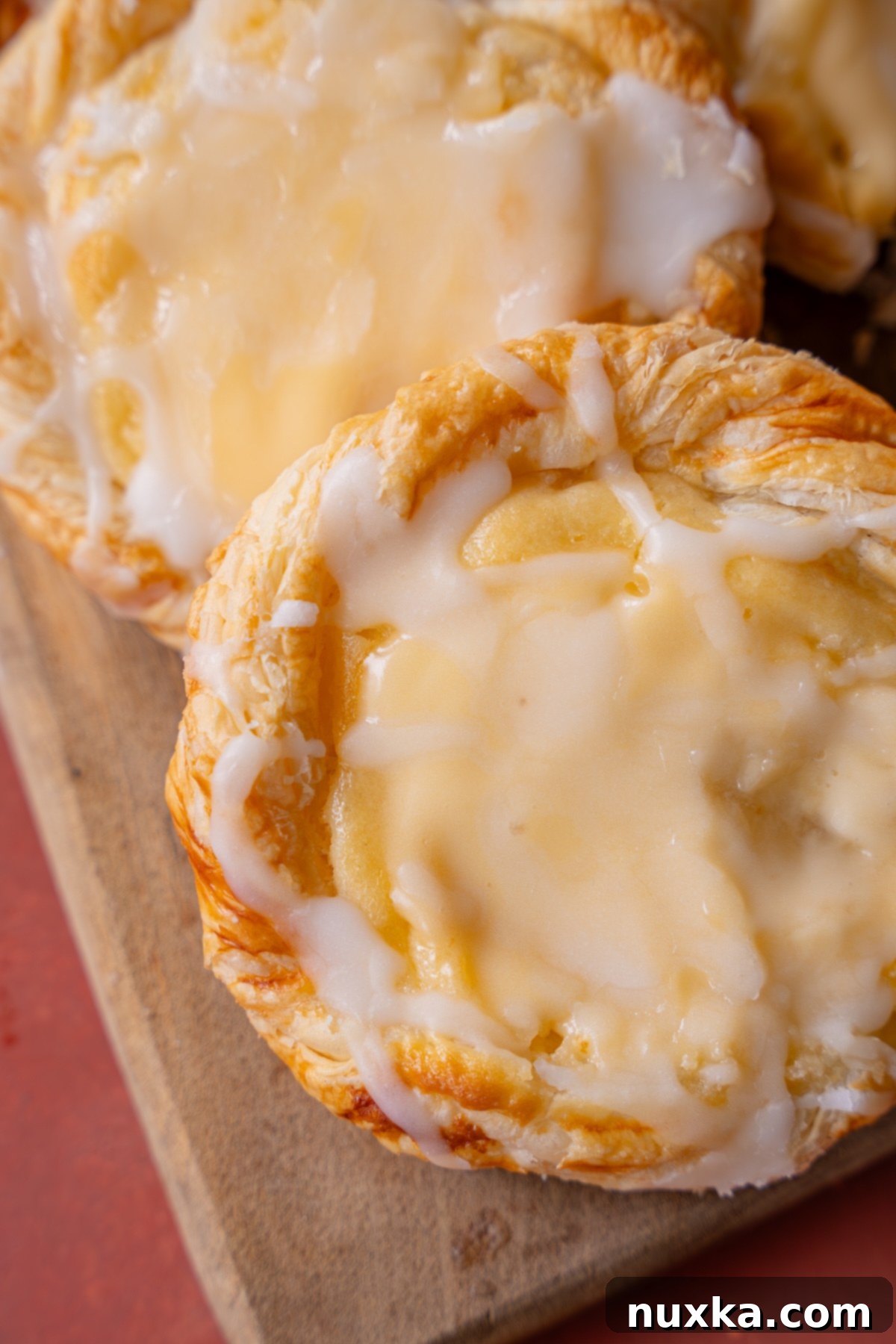 Zoomed in image of a perfect cream cheese danish with powdered sugar glaze, highlighting the flaky pastry and creamy center