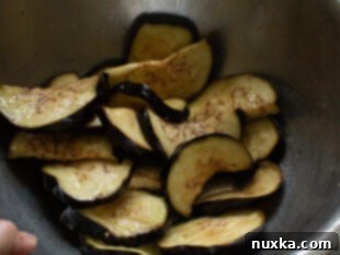 Tossing eggplant slices with olive oil, salt, and pepper for roasting