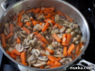 Mushrooms, carrots, and onions sautéed in a pan for mushroom pilaf.