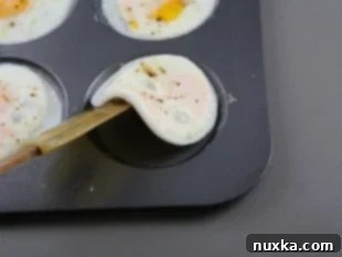 Baked egg patties removed from muffin tin with a spatula