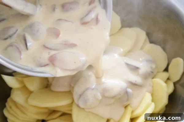 Mixing hot dogs and creamy sauce with sliced potatoes