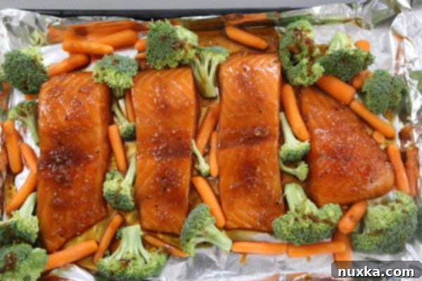 salmon and vegetables baking on a sheet pan