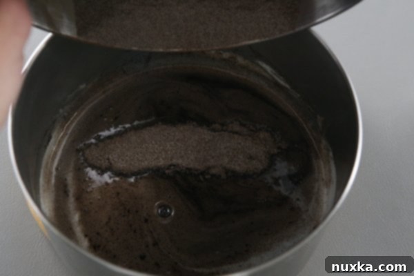 Whisking cocoa mixture into melted butter and water in a saucepan.