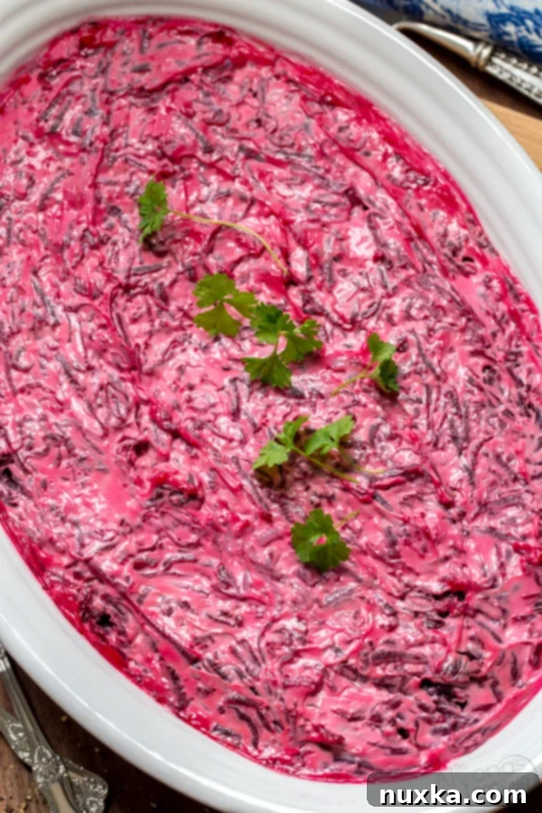 shuba herring fish salad that is layered with beets, potatoes, carrots and mayo on a white oval dish