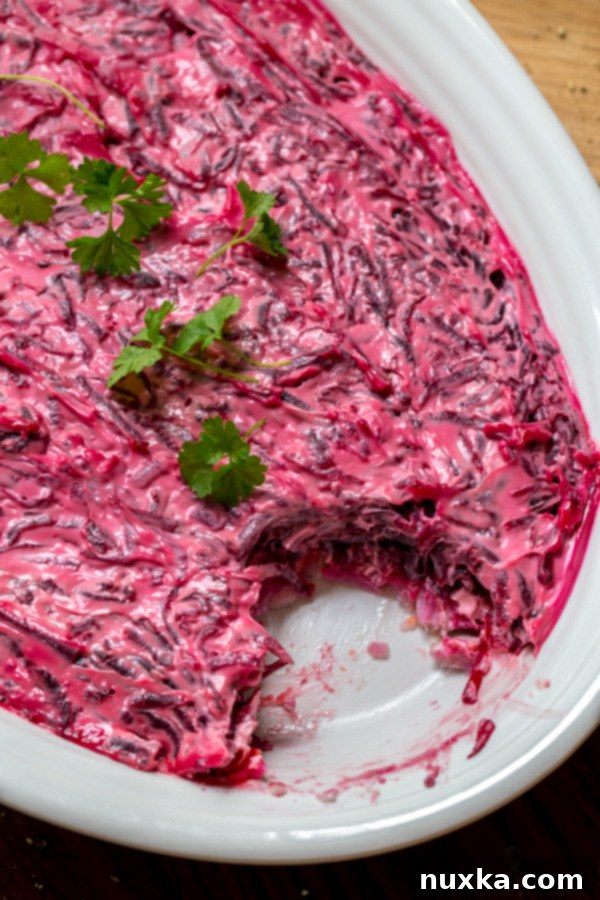 Shuba Salad with herring fish, cooked potatoes, carrots, beets and mayo on an oval serving dish