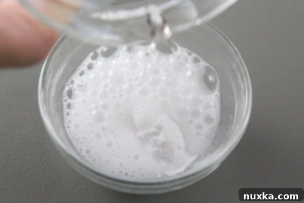 how to dissolve baking soda and vinegar image Baking soda dissolved in vinegar, creating a fizzy reaction before being added to the honey cake batter